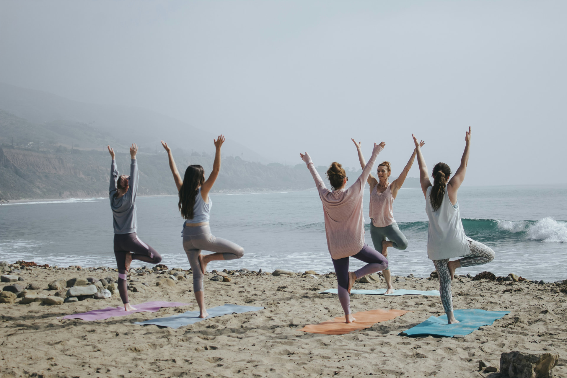 Grupp som tränar yoga tillsammans vid havet